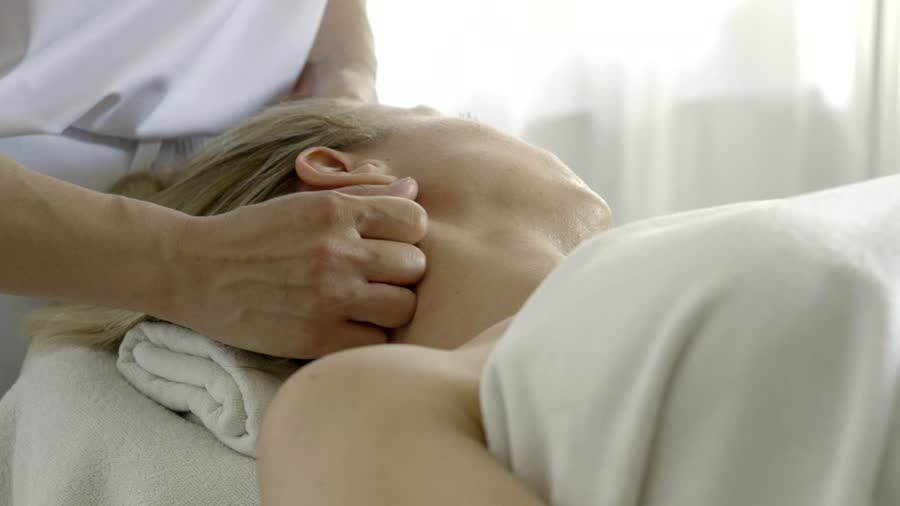 Masoterapeuta masajeando el cuello de una persona recostada